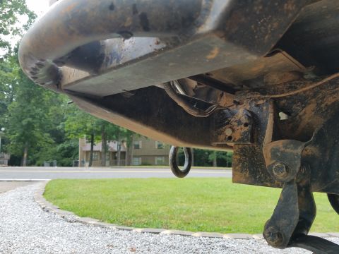 1988 Ford Bronco - The underside of a vehicle shows a tow hook and exposed wiring, with a residential area in the background.