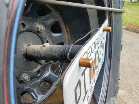 1988 Ford Bronco - A close-up view of a vehicle's rear tire and license plate assembly, with visible text on the plate.