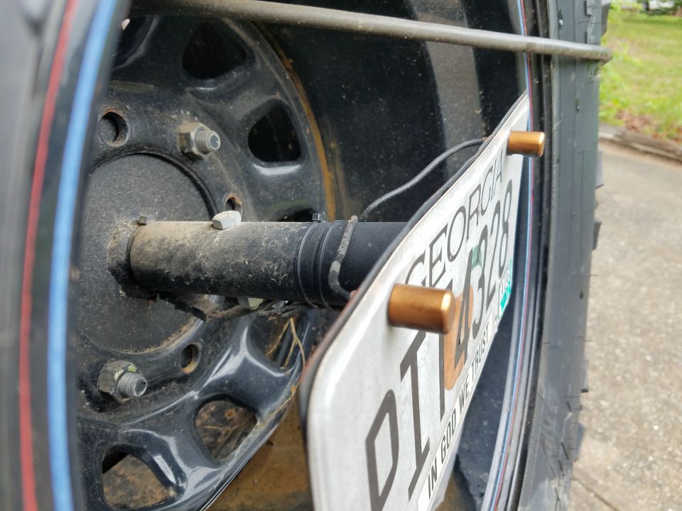 Rear tire and license plate assembly on a vehicle, showing a black wheel and a Georgia license plate