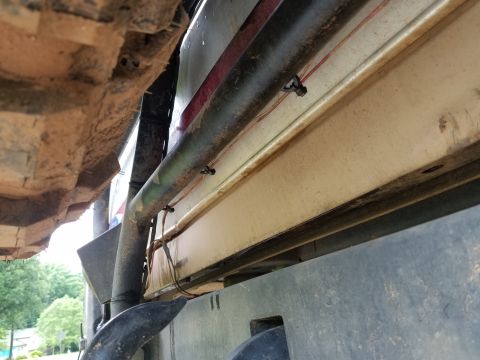 1988 Ford Bronco - A close-up shot reveals the undercarriage of a vehicle, showing its frame, suspension components, and exhaust system.