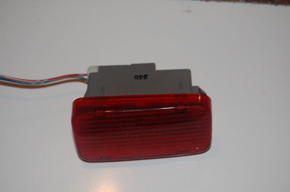 Red taillight assembly with gray connector and wires, text 'R9K' visible
