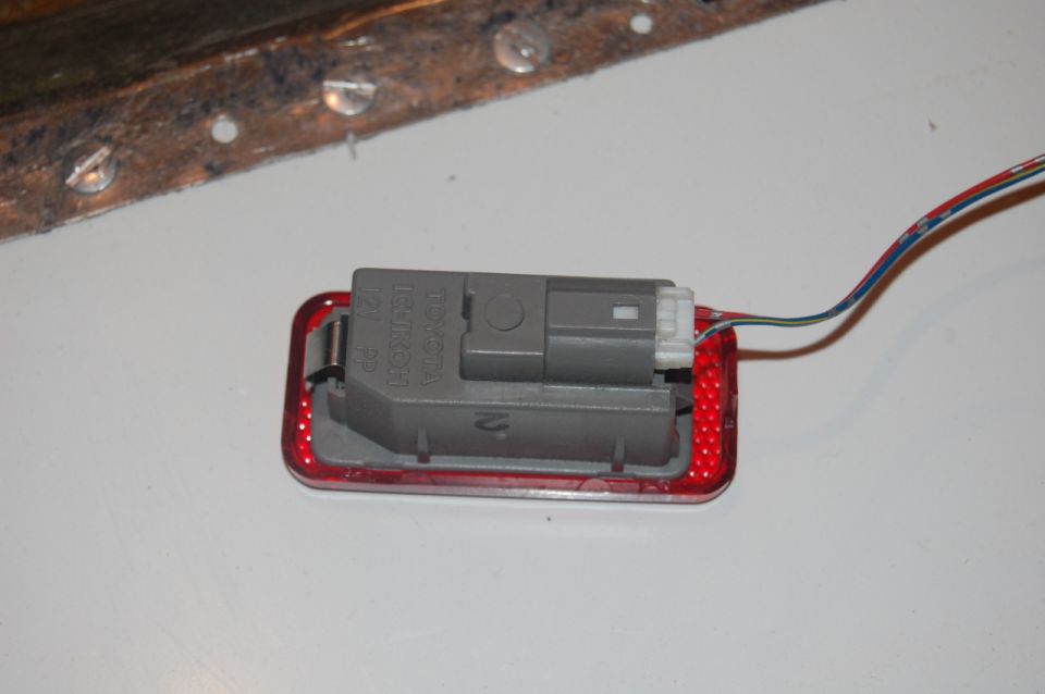 Red reflector with gray electrical connector and wires attached