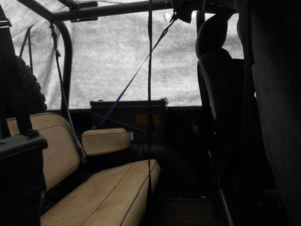 Interior of a 1972 Ford Bronco with tan seats, spare tire, and ammo can.
