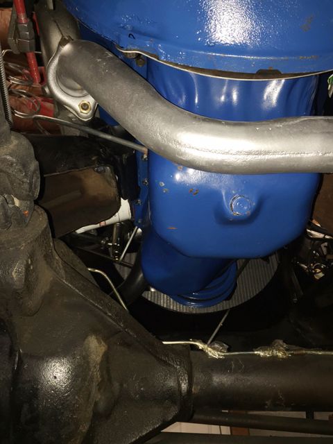 1978 Ford Bronco - A close-up view of a blue engine component and a silver exhaust pipe in a vehicle. The black differential housing is visible in the foregro…