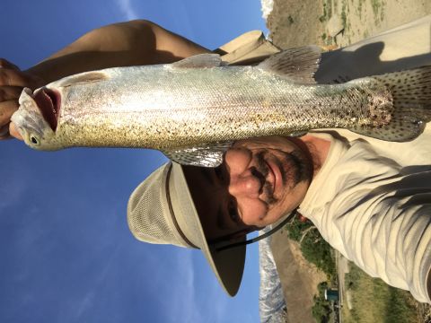 1997 Dodge 3500 - A man holds up a large fish he has caught, with a clear blue sky in the background.