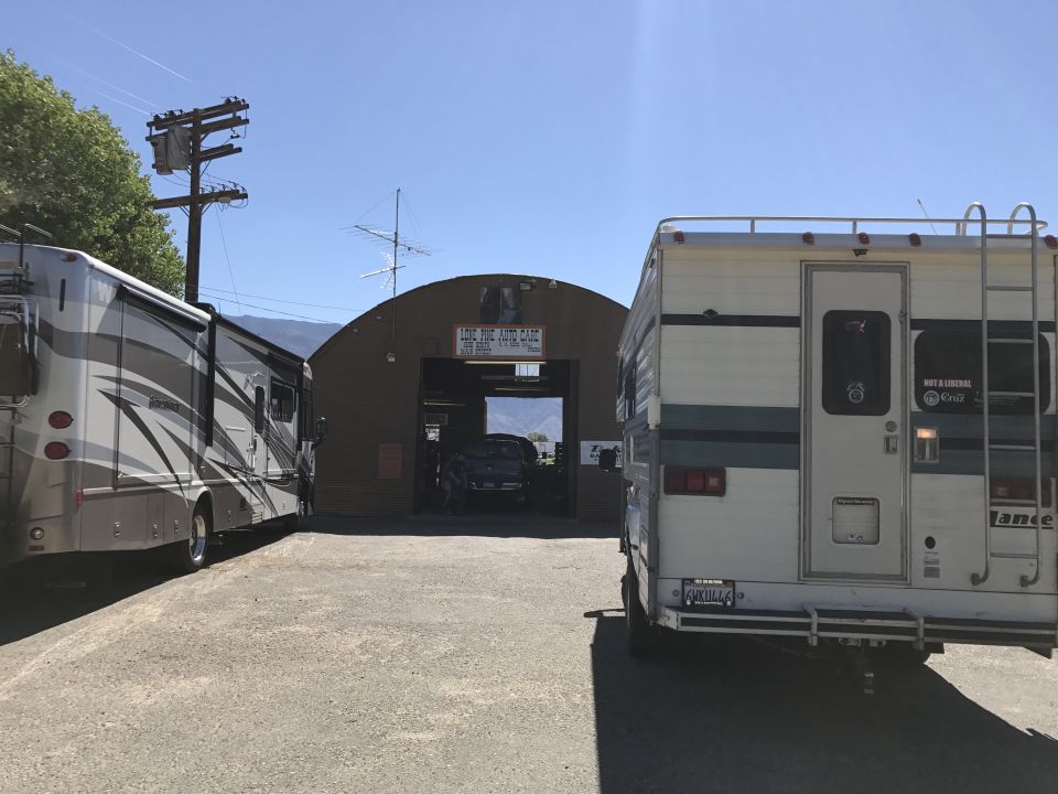 Two RVs parked outside an auto repair shop.