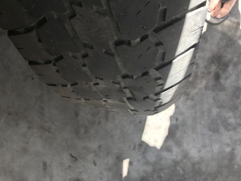 1997 Dodge 3500 - A close-up, low-angle shot of the tread pattern on a tire, likely from a truck or heavy-duty vehicle. The tire is casting a shadow on the c…