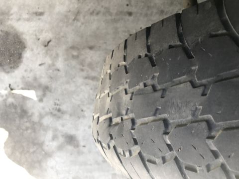 1997 Dodge 3500 - A close-up, angled view of a worn tire tread on a concrete surface. The tire has a distinct pattern of blocks and grooves.