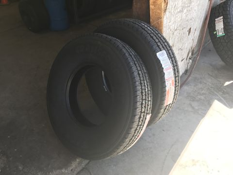 1997 Dodge 3500 - Two new tires are displayed leaning against a wooden structure. The tires have white and red labels with text and barcodes visible.