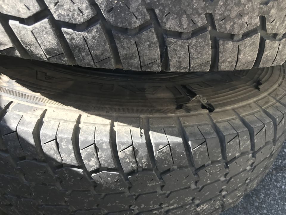 Close-up of stacked tires, the bottom one has a tear in the sidewall.