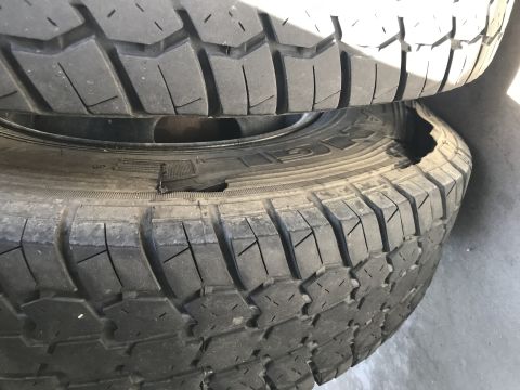 1997 Dodge 3500 - Two stacked tires are shown, with the bottom tire exhibiting a significant sidewall puncture. The tread pattern of both tires is visible.