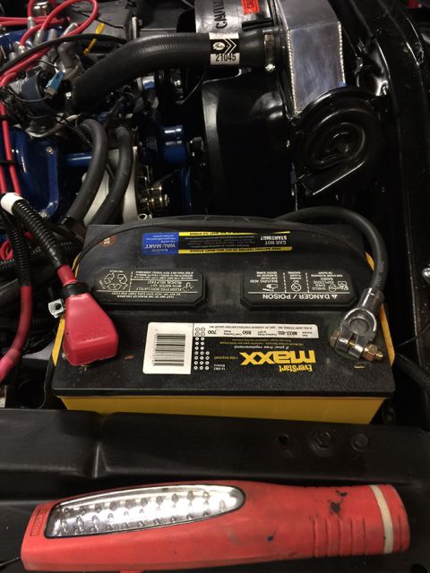 1978 Ford Bronco - A close-up view of a car battery and engine components in a vehicle's engine bay. The battery is a black EverStart Maxx with a yellow base,…
