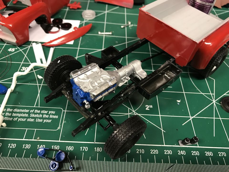 Model truck chassis with engine and transmission assembly on a green cutting mat.