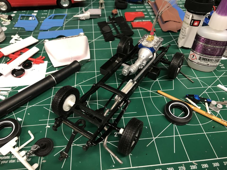 Model car chassis assembly with engine, transmission, wheels, and tools.