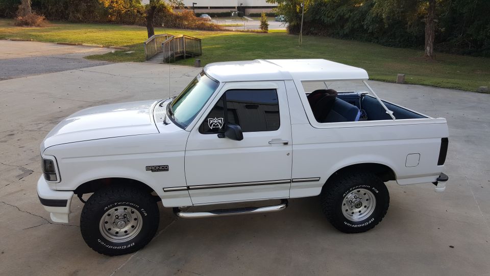White 1990s Ford Bronco parked on concrete driveway.