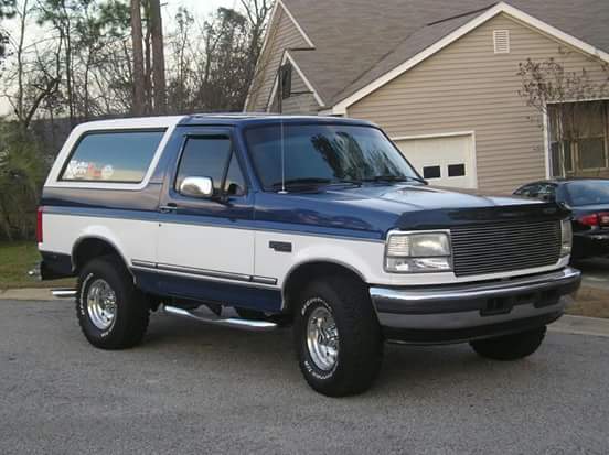 1995 Ford Bronco, two-tone blue and white, parked in front of a house.
