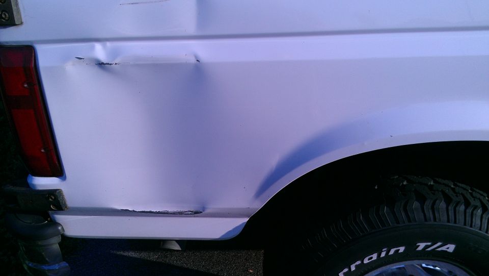 White SUV rear quarter panel with dent. Side view