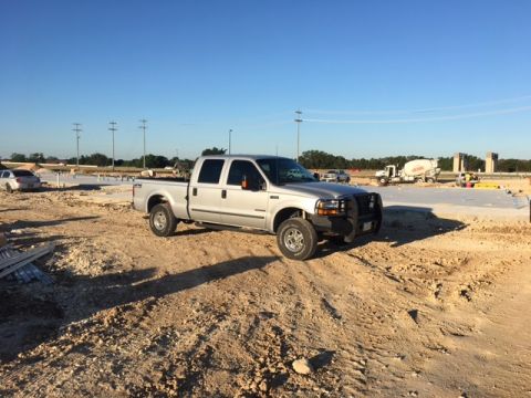2004 Ford F-150 - A silver 2004 Ford F-150 pickup truck is parked on a dirt lot with construction equipment in the background.