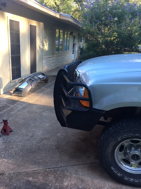 2004 Ford F-150 - A truck is parked in front of a house with a chrome bumper lying on the ground nearby.