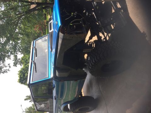 1974 Ford Bronco - This 1974 Ford Bronco is shown with its hood open, revealing the engine bay and large off-road tires.