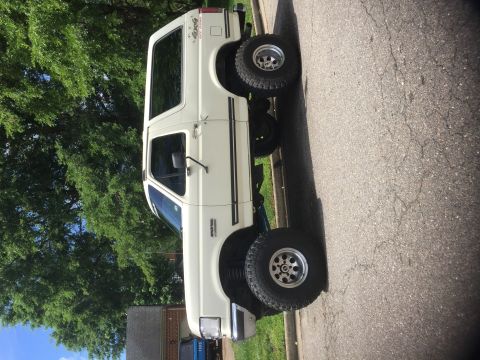 1974 Ford Bronco - This white Ford Bronco SUV is seen from the side, aftermarket wheels and a lifted suspension.