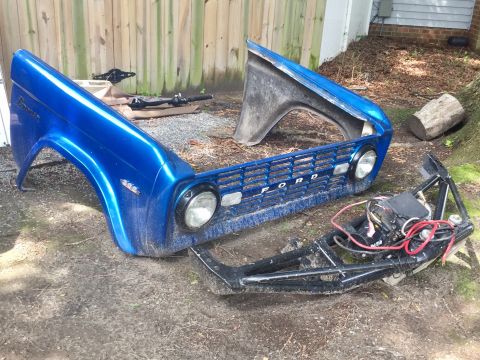 1974 Ford Bronco - Disassembled 1974 Ford Bronco front clip and frame section with engine components visible.