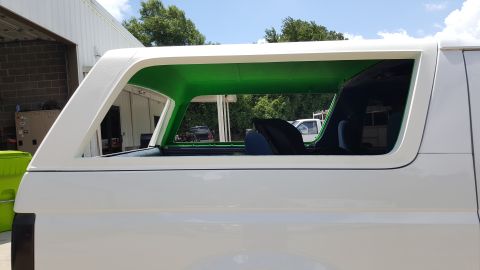 1995 Ford Bronco - The interior of this white SUV is painted a vibrant green, contrasting with its exterior.