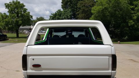 1995 Ford Bronco - Rear view of a white Ford Bronco with aftermarket green trim on the roll bar.