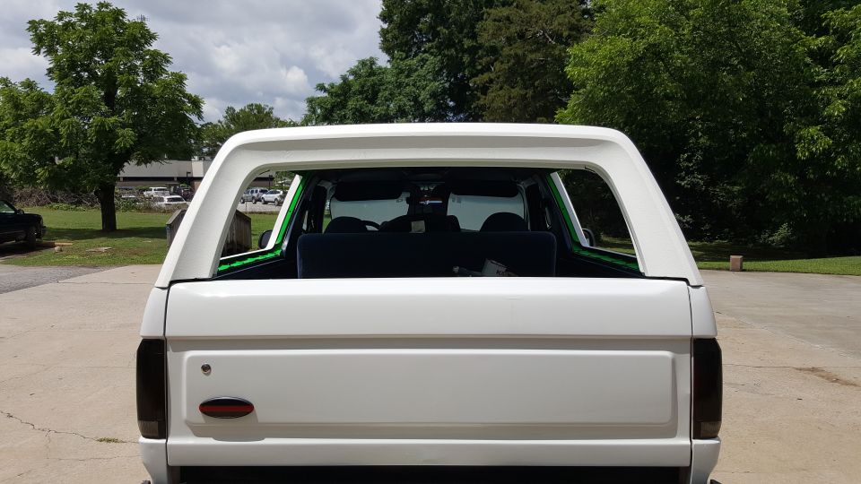 White Ford Bronco rear view. Tinted taillights, aftermarket green trim around rear window