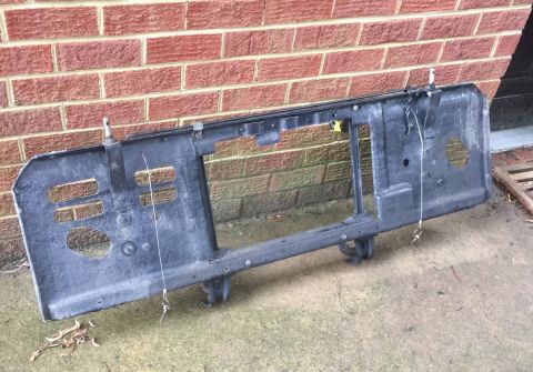 1974 Ford Bronco - Front grille support frame for a 1974 Ford Bronco, shown outdoors against a brick wall.