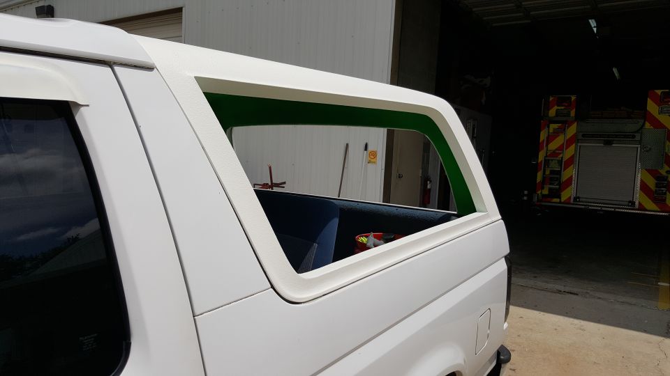 Side view of a white SUV with a removable hardtop, showing the rear quarter window with green trim