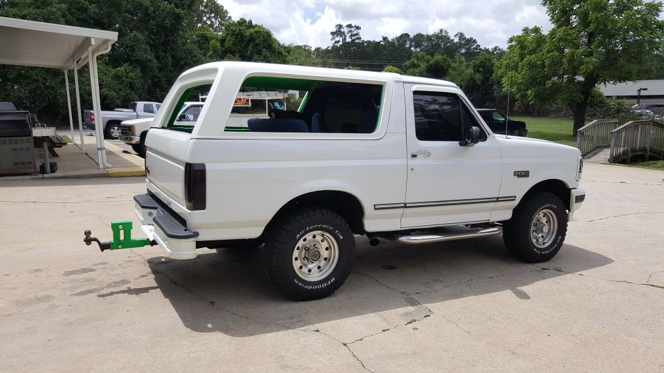 White Ford Bronco with green trailer hitch, side view