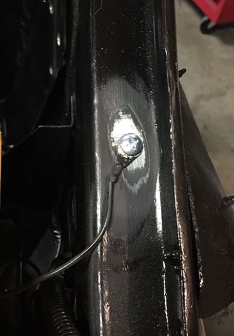 1978 Ford Bronco - Detail of a black metal frame component with a bolt and wire connection.