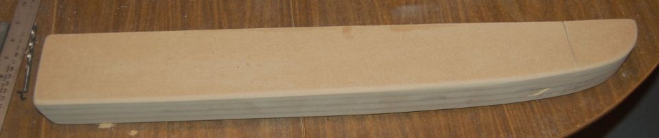 Wooden piece with rounded end and ruler and drill bit nearby