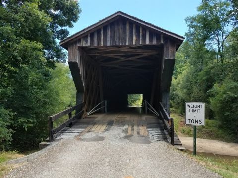 1978 Ford Bronco - A wooden covered bridge spans a roadway, with a sign indicating a weight limit of 3 tons.