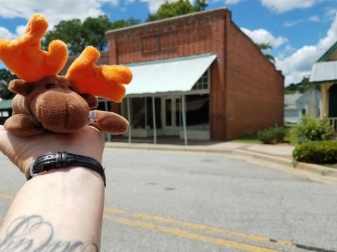 1978 Ford Bronco - A plush moose toy is held up in front of a brick building on a sunny day.