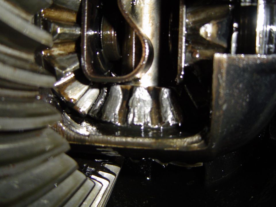 Close-up of a ring-and-pinion gear set inside a differential coated in oil