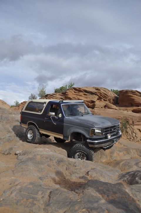 1991 Ford Bronco - This 1991 Ford Bronco is shown off-roading through a , rocky landscape under a cloudy sky.