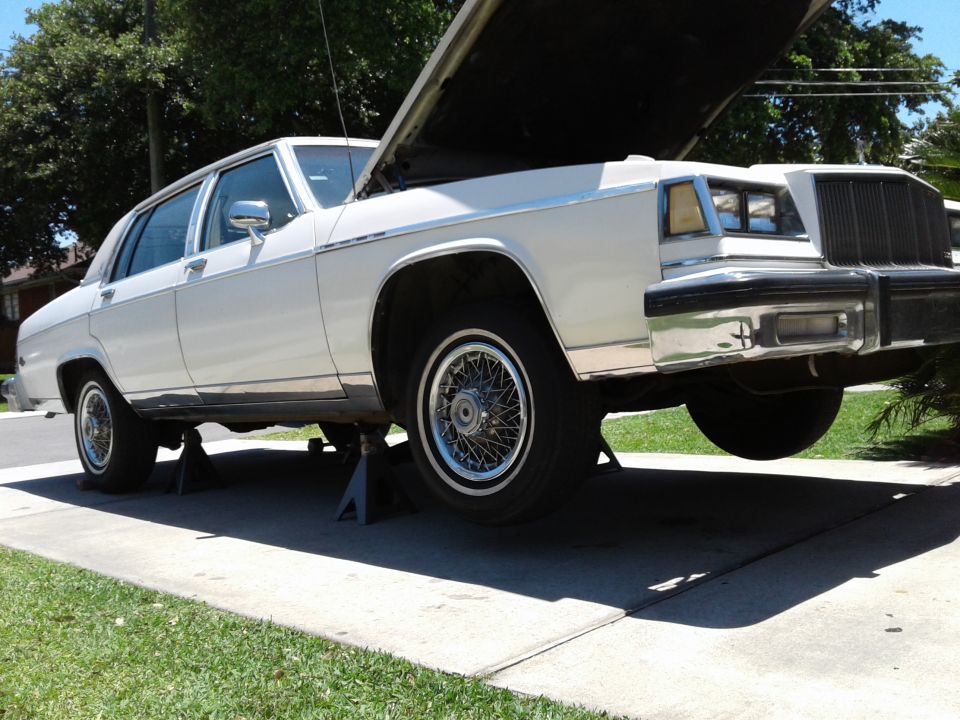 White 1984 Buick Electra on jack stands, hood open, 3/4 front view