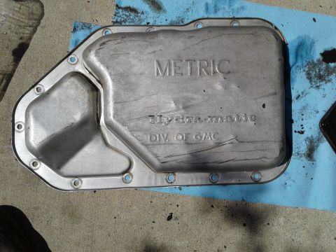 1984 Buick Electra - A metal transmission pan with embossed text sits on a blue shop towel.