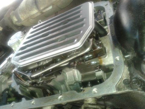 1984 Buick Electra - Close-up view of a transmission pan and filter, showing internal components and fluid.