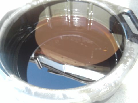 1984 Buick Electra - Close-up of an oil filter housing filled with brown oil, reflecting the blue sky.