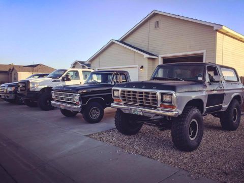 1968 Ford F-100 - Several Ford trucks and SUVs are lined up in a driveway. The Bronco in the foreground appears to be from the late 1970s.
