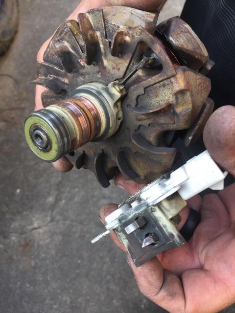 1988 Ford Bronco - A close-up view of a worn alternator component, held by a person's hands.