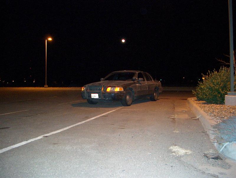 Dark 2001 Ford Crown Victoria parked at night, front-left view, with a full moon overhead