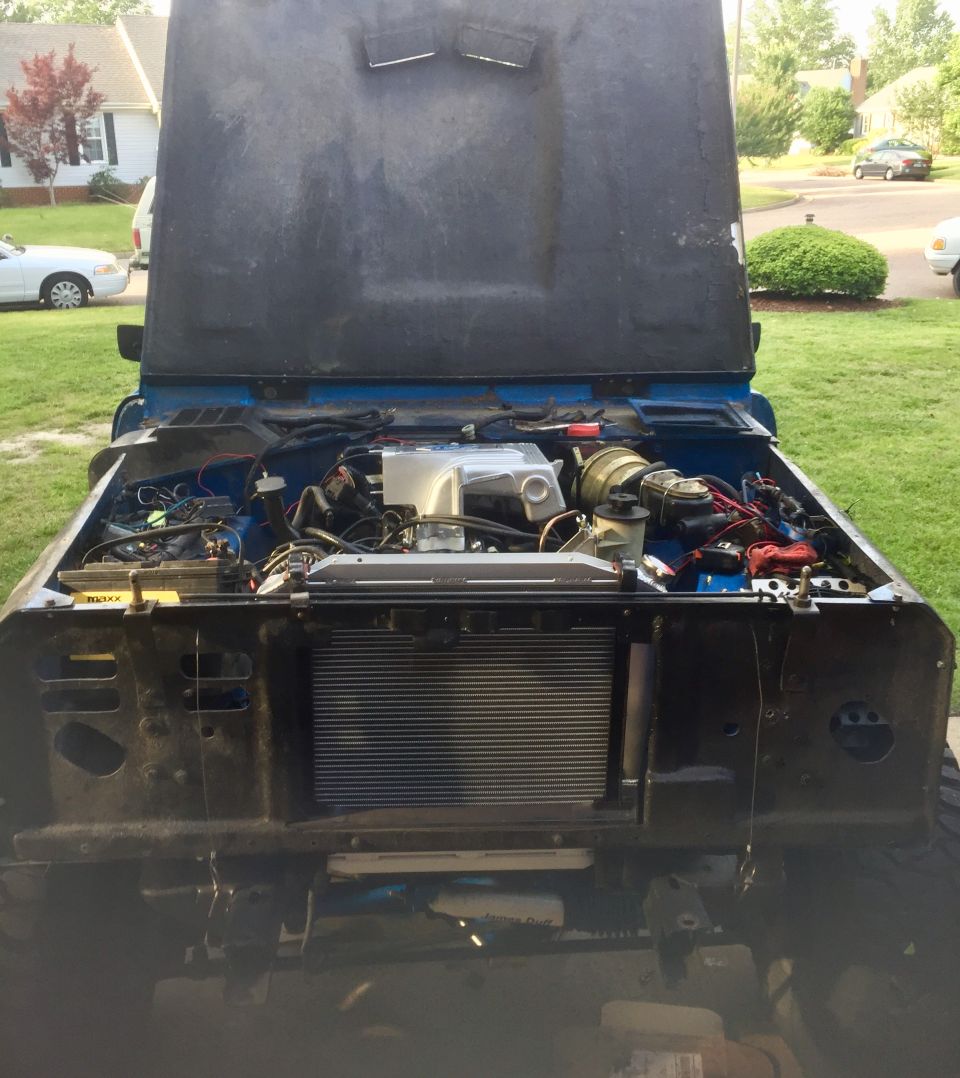 Blue vehicle engine bay with hood open, showing engine and radiator