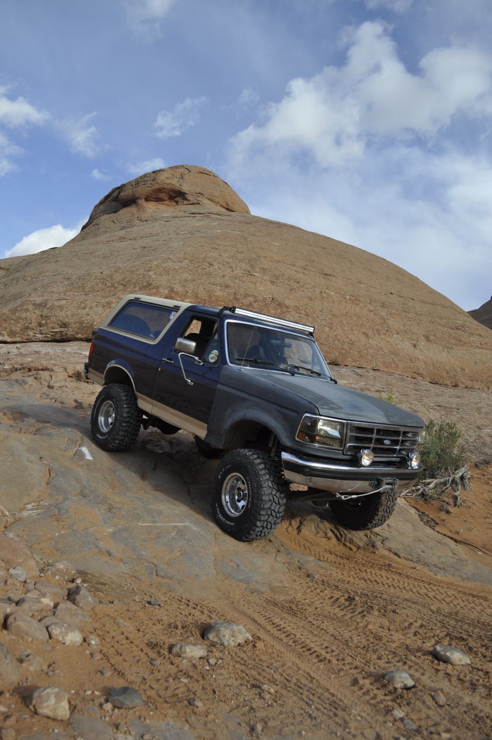 Dark blue 1991 Ford Bronco climbing a rocky desert trail