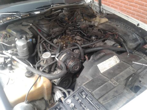 1984 Buick Electra - The engine bay of a vehicle, showing various components and a set of tools laid out.