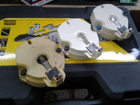 1984 Buick Electra - Two white and one tan distributor caps are shown, resting on a black surface with yellow packaging in the background.