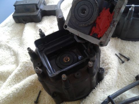 1984 Buick Electra - A disassembled car distributor cap and rotor, showing internal components and red sealant, rests on a white towel.